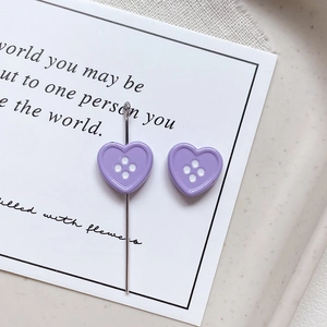 Detailed view of a lavender heart-shaped four-hole button with a metal sewing needle