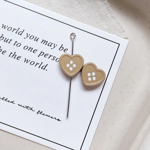 Close-up of heart-shaped button beads in light brown resin with four holes for DIY jewelry
