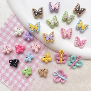 Detailed view of colorful lacquer butterfly beads for DIY jewelry making on checkered fabric