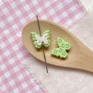 Close-up of light green butterfly beads on a wooden spoon for DIY jewelry making