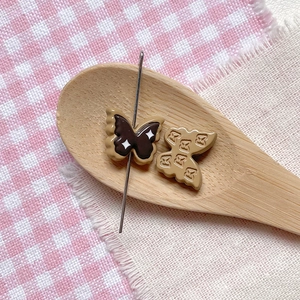 Macro detail of butterfly charms in a wooden spoon for DIY jewelry and crafts
