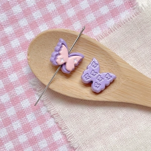 Detail of purple and pink butterfly beads for DIY jewelry on a wooden spoon