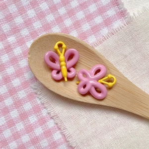 Detail of pink and yellow butterfly beads for DIY jewelry on a wooden spoon