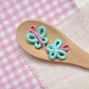 Macro detail of mint green and pink butterfly charm with alloy paint finish