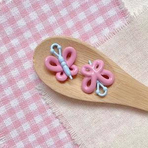 Macro shot of butterfly DIY bead accessories on a wooden spoon with plaid fabric