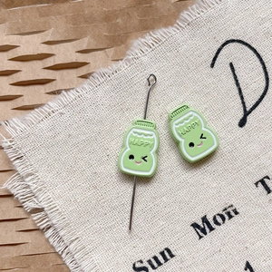 Vue macro de breloques émaillées vertes Happy pour bijoux DIY et chaînes de téléphone