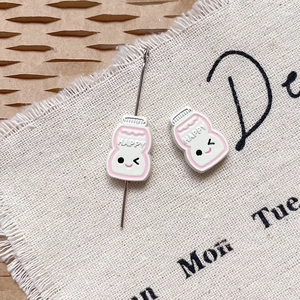 Vue macro de breloques bouteille de lait Happy avec émail rose pour bijoux DIY