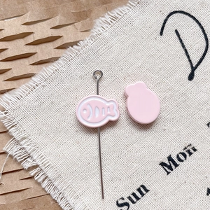 Détail macro de breloques poisson en émail rose et épingles métalliques pour bijoux DIY