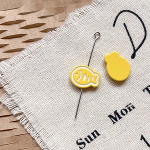 Détail macro d'épingle poisson émail jaune avec longue aiguille sur tissu texturé