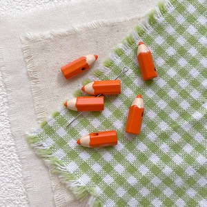 Macro detail of orange pencil-shaped alloy beads for DIY jewelry making on fabric