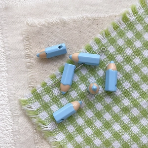Macro detail of light blue enamel pencil charms for DIY jewelry making and handmade crafts