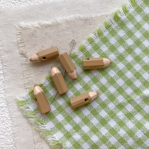 Macro view of pencil-shaped resin beads in coffee and beige for DIY jewelry projects