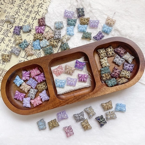 Détail de perles papillon colorées en verre dans un plateau en bois pour bijoux DIY