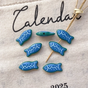 Close-up of tropical fish shaped beads with blue enamel finish for DIY jewelry crafting