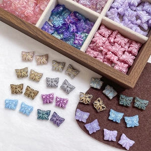 Gros plan de perles papillon en verre coloré avec bords dorés pour bijoux artisanaux