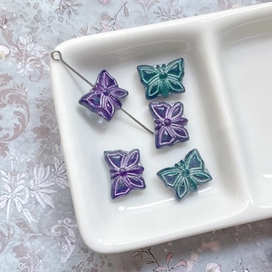Vue détaillée de perles papillon en verre avec accents dorés et fini irisé pour bijoux DIY