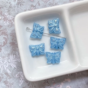 Vue macro de perles papillon en verre tchèque bleu clair nacré pour création de bijoux DIY