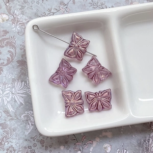 Détail macro de perles papillon en verre violet irisé avec bords dorés pour bijoux DIY