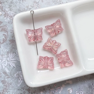 Détail macro de perles papillon en verre rose avec revêtement aurora et bordure dorée