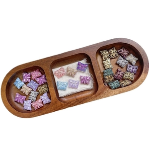 Perles papillon en verre tchèque colorées avec bords dorés dans un plateau en bois