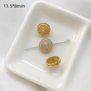 Primer plano de cuenta dorada calada de 11,5x8 mm y conector con piedra preciosa rosa