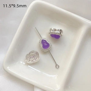 Detalle macro de dijes de calabaza morada con circonitas y artesanía de plata calada