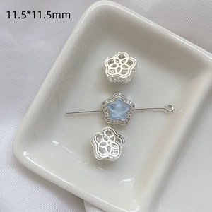 Detalle de cuentas de flores plateadas con estrellas azules y circones para joyería