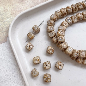Macro shot of vintage Czech style textured glass beads in cream with brown details