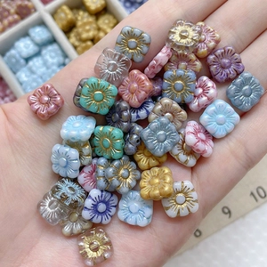 Macro detail of square Czech glass flower beads with golden edges and matte finish