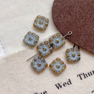 Macro detail of square amber glass beads with light blue floral engraving for DIY jewelry