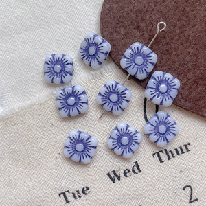 Macro shot of square Czech glass beads featuring purple Hawaiian flower Picasso patterns