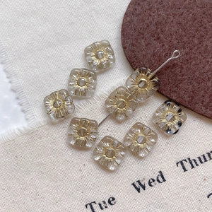 Macro detail of square Czech glass beads with golden sunburst pattern for DIY jewelry
