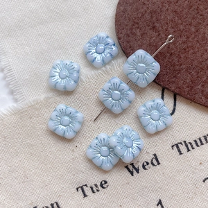 Macro detail of light blue glass flower beads with metallic luster for DIY jewelry making