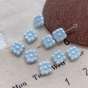 Detail view of light blue pearlescent square flower glass beads for DIY jewelry making