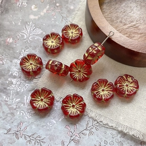 Macro view of red glass flower beads with gold accents for DIY jewelry making