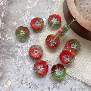Detail of red flower beads with gold accents and metal hooks for DIY jewelry making