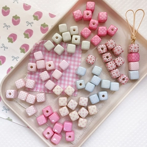 Macro view of pastel square acrylic beads with strawberry and heart patterns for DIY crafts