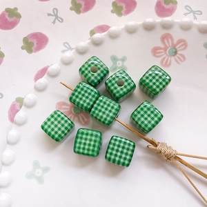 Close-up of green and white checkered square beads on a decorative white ceramic plate