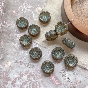 Close-up of Czech glass plum blossom beads with vintage bronze texture and petal details