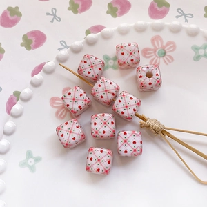 Close-up of square DIY beads with pink grid and red hearts in a ceramic plate