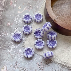 Macro detail of purple and white glass flower beads for handmade jewelry on wooden tray