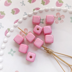 Detailed view of pink and white checkered square ceramic beads for DIY jewelry