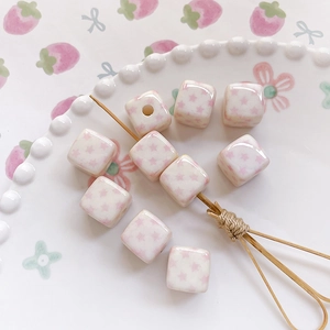 Macro shot of white ceramic cube beads with pink star patterns for DIY jewelry making