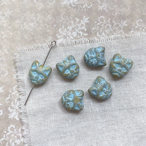 Detail of vintage blue cat head beads with gold engraving and functional through-hole