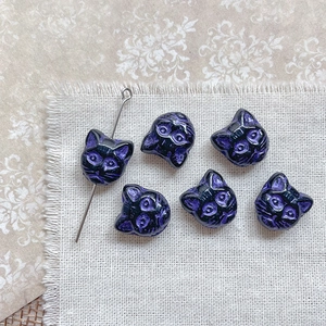 Macro detail of cat-shaped glass beads in dark purple for DIY jewelry making