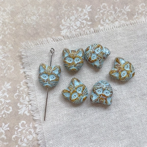 Macro shot of sky blue cat-shaped beads with vintage textured glaze for DIY jewelry