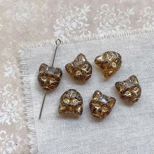 Macro detail of amber cat-head glass beads with gold accents for DIY jewelry making