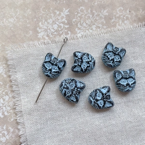 Macro view of vintage cat-shaped glass beads for DIY jewelry making on linen background