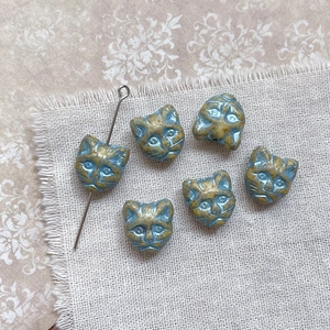 Macro view of blue and gold vintage cat head glass beads on rustic linen fabric background