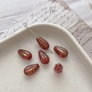 Macro shot of amber red glass teardrop beads with gold glaze finish for jewelry DIY